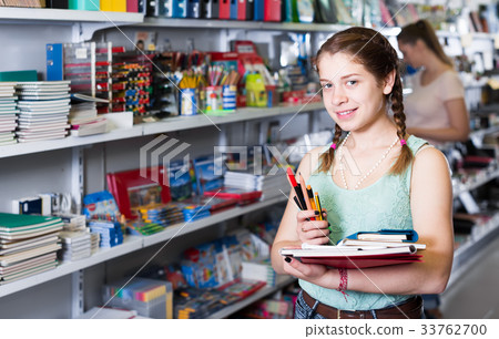 Beautiful teenager buying products in stationery shop Beautiful teenager buying products in stationery shop 33762700