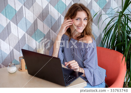 A female freelancer is talking on a phone while 33763748