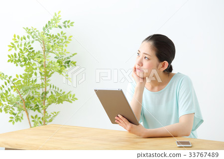 一個女人看著一台平板電腦 33767489
