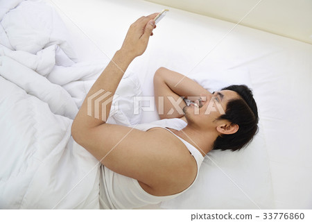 Handsome asian man using cellphone while lying 33776860