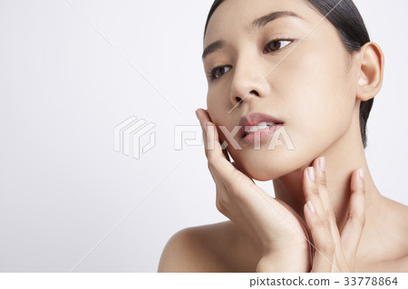 A beautiful model is putting her hand on her cheek 33778864