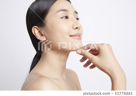 A model is putting her hand on her chin and smiling 33778881