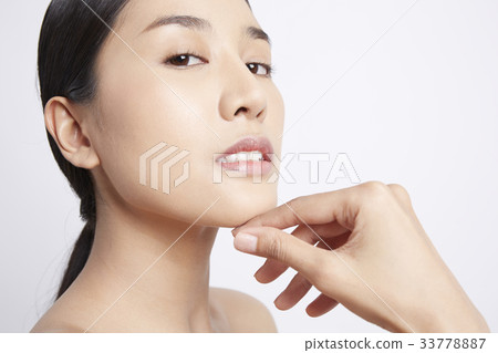 A model is putting her hand on chin and looking at camera 33778887