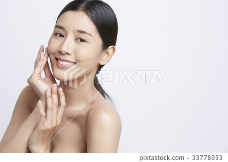 an attractive girl is touching her face and smiling 33778953