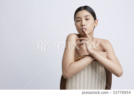 a girl is putting a finger on her lip and posing with a chair 33778954