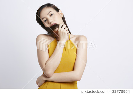 a girl in yellow clothes is holding her hair and posing 33778964