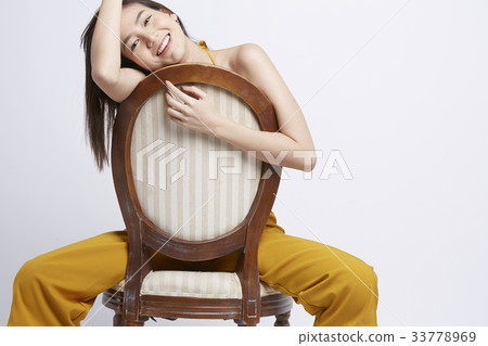 photo of a happy girl straddling on a chair indoors photo of a happy girl straddling on a chair indoors 33778969