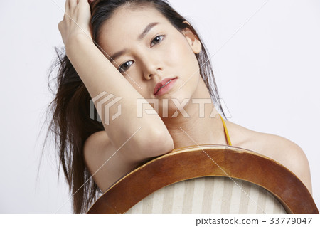 a beautiful asian girl is sitting on chair and looking at the camera 33779047