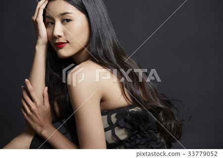 portrait of woman holding her face and smiling on black background 33779052
