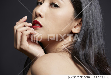 portrait of woman touching her face and looking at camera 33779062