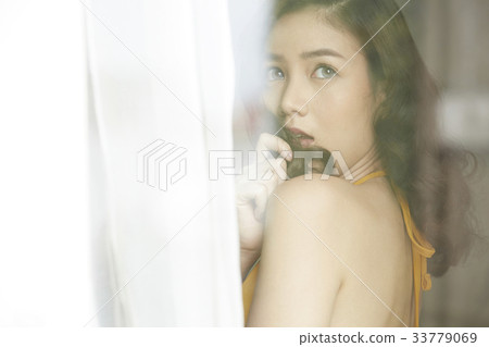 portrait of beautiful woman holding her hair behind a curtain 33779069
