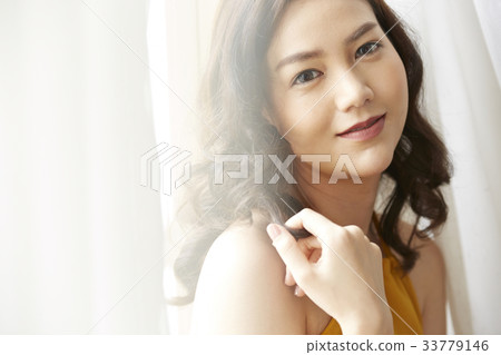 A Thai girl is smiling beside the white curtain 33779146
