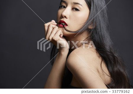 portrait of Asian woman touching her chin on black background 33779162