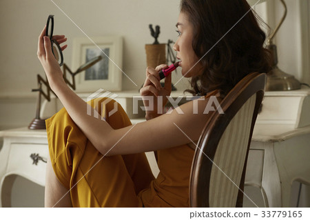 Woman performs makeup on her lips in her room 33779165