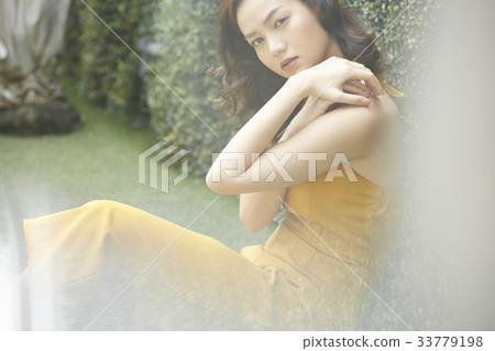 The picture of a beautiful girl sitting on the grass and posing 33779198