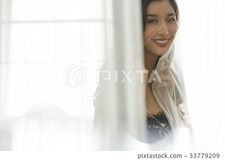 The picture of girl smiling and holding the curtain 33779209