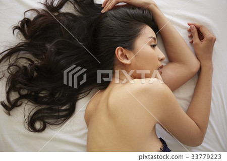 The picture of a girl with a long hair lying on the bed 33779223