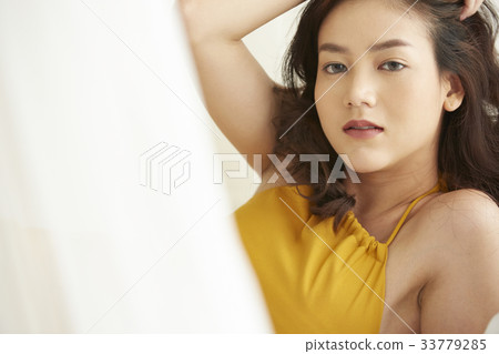 An Asian young woman is posing while looking at camera inside. 33779285