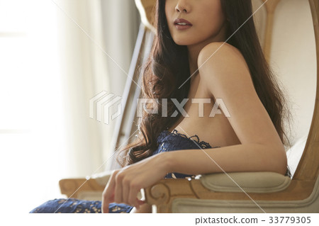An elegant lady is posing and sitting on the couch inside. 33779305
