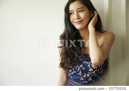photo of a woman leaning against a wall and smiling. 33779338