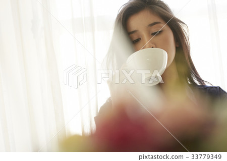 photo of a woman holding a cup and drinking. 33779349