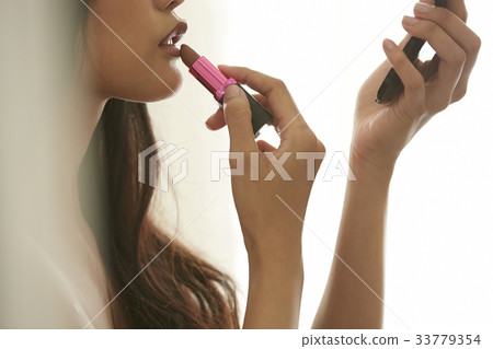 photo of a woman holding a lipstick and making up herself. photo of a woman holding a lipstick and making up herself. 33779354