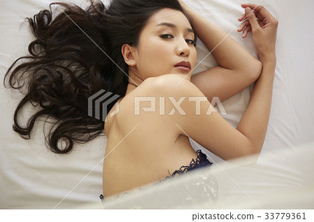 photo of a woman lying on a bed and looking at camera. 33779361