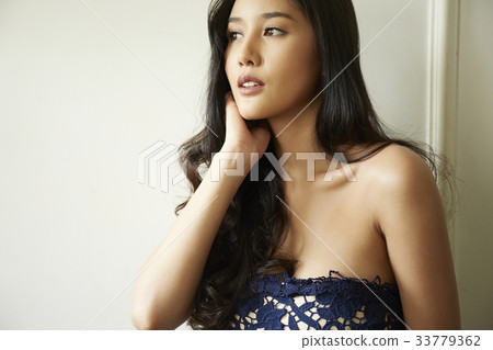 photo of a woman looking at something with a hand on neck. 33779362