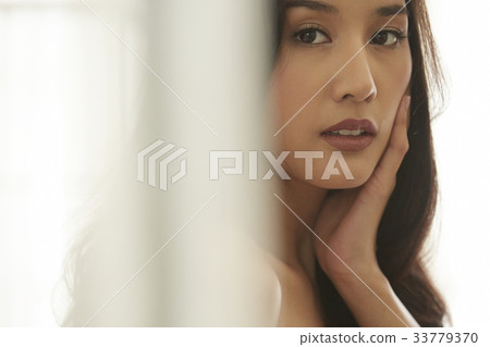 photo of a woman looking at camera with a hand on cheek. 33779370