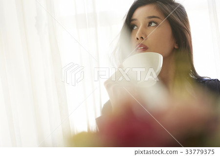 photo of a beautiful woman holding a cup and looking up. 33779375