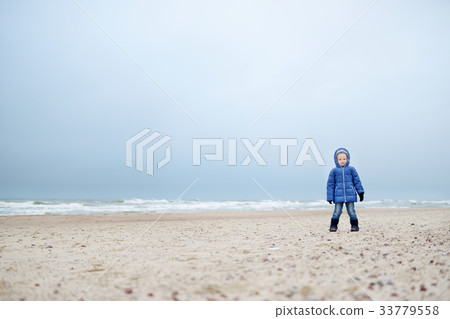 Adorable little girl playing by the ocean on winter day 33779558