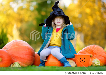 Adorable little girl wearing halloween costume having fun on a pumpkin patch 33779607