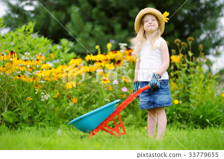 Adorable little girl having fun with a toy wheelbarrow Adorable little girl having fun with a toy wheelbarrow 33779655