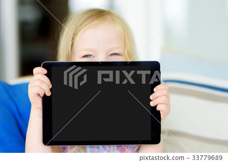 Smart little schoolgirl with digital tablet in at home 33779689
