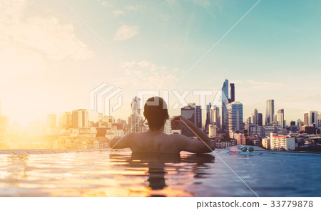 a man relax in swimming pool in sunrise, in city a man relax in swimming pool in sunrise, in city 33779878