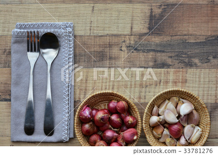 Spoon, fork, onion and garlic on wood background.  33781276