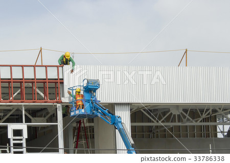 Workers in a baskets are installing sheet building 33786338