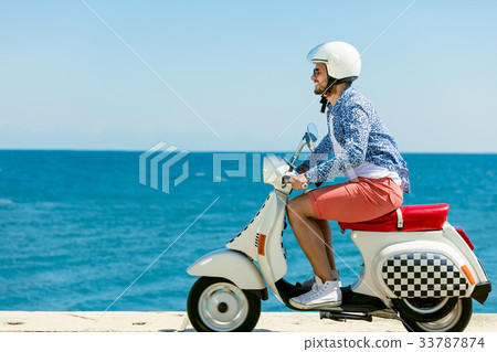 Handsome man posing on a scooter in a vacation 33787874