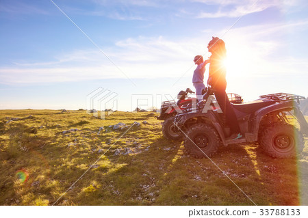 Rear view of young pair near atv. Man is showing Rear view of young pair near atv. Man is showing 33788133