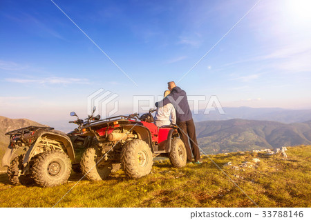 Rear view of young pair near atv. Man is showing 33788146