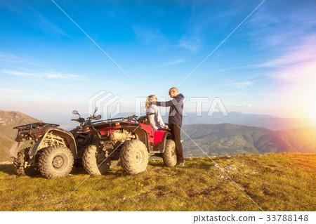 Rear view of young pair near atv. Man is showing 33788148