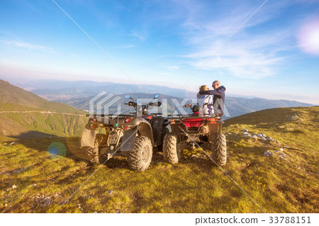 Rear view of young pair near atv. Man is showing Rear view of young pair near atv. Man is showing 33788151