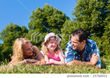 Father, mother, daughter lying on meadow in grass 33788932