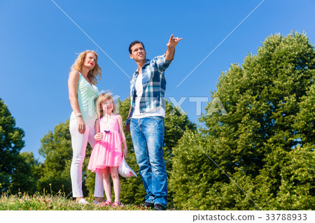 Young family on field, Dad pointing at something 33788933
