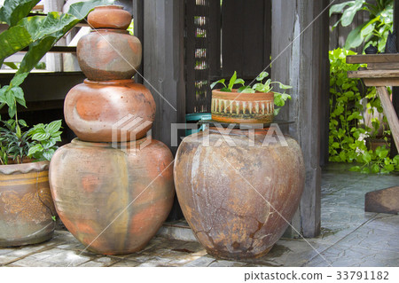 Old orange earthen jars stacked next to a wooden Old orange earthen jars stacked next to a wooden 33791182