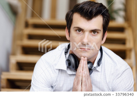 Portrait of young man sitting at the stairs in office Portrait of young man sitting at the stairs in office 33796340