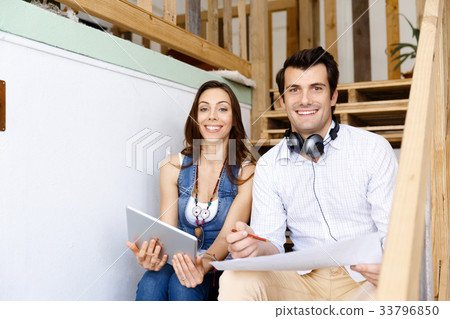 Portrait of two young people sitting at the stairs in office Portrait of two young people sitting at the stairs in office 33796850