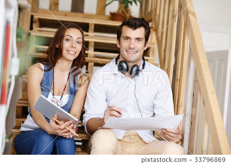 Portrait of two young people sitting at the stairs in office 33796869