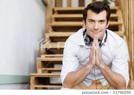 Portrait of young man sitting at the stairs in office Portrait of young man sitting at the stairs in office 33796890