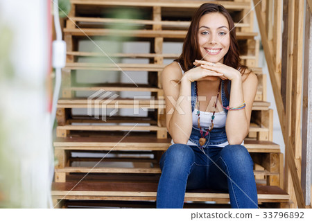 Portrait of young woman sitting at the stairs in office Portrait of young woman sitting at the stairs in office 33796892